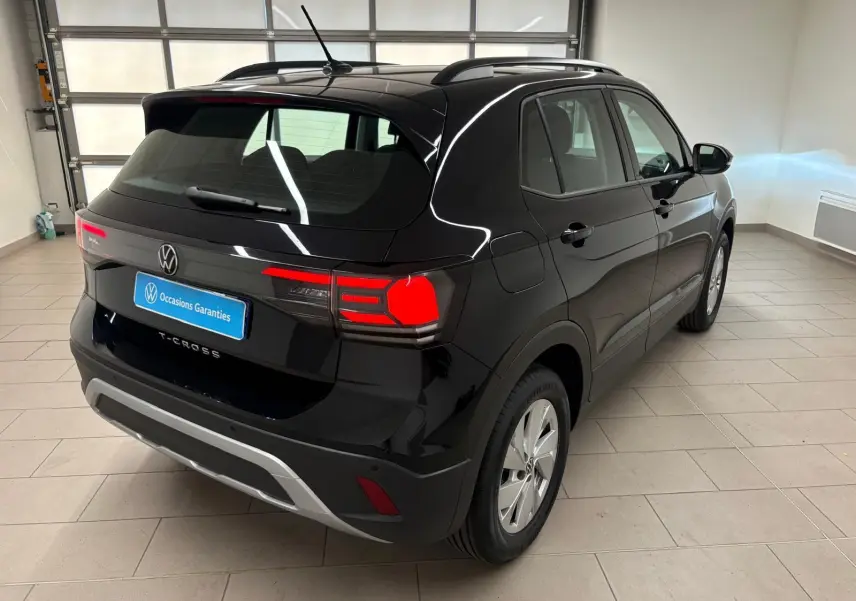 Volkswagen T-Cross noir intense vu en 3/4 arrière droit dans un garage avec feux arrière allumés.