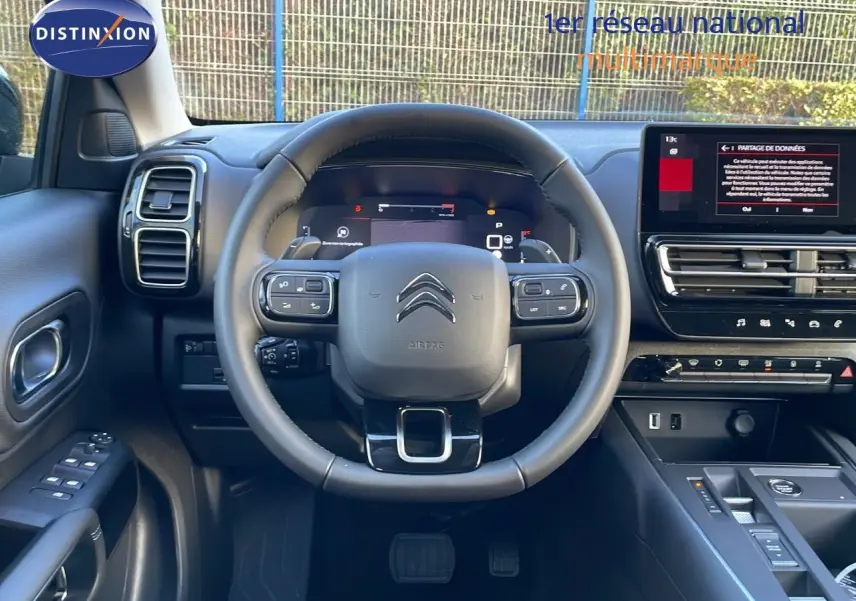 Vue intérieure centrée sur le volant et tableau de bord du Citroën C5 Aircross noir, avec écran tactile et commandes au volant.
