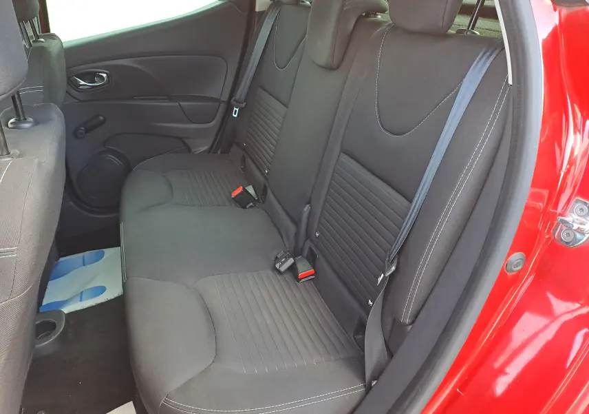 Vue intérieure côté droit sur la banquette arrière noire de la Renault Clio IV rouge avec porte arrière ouverte.
