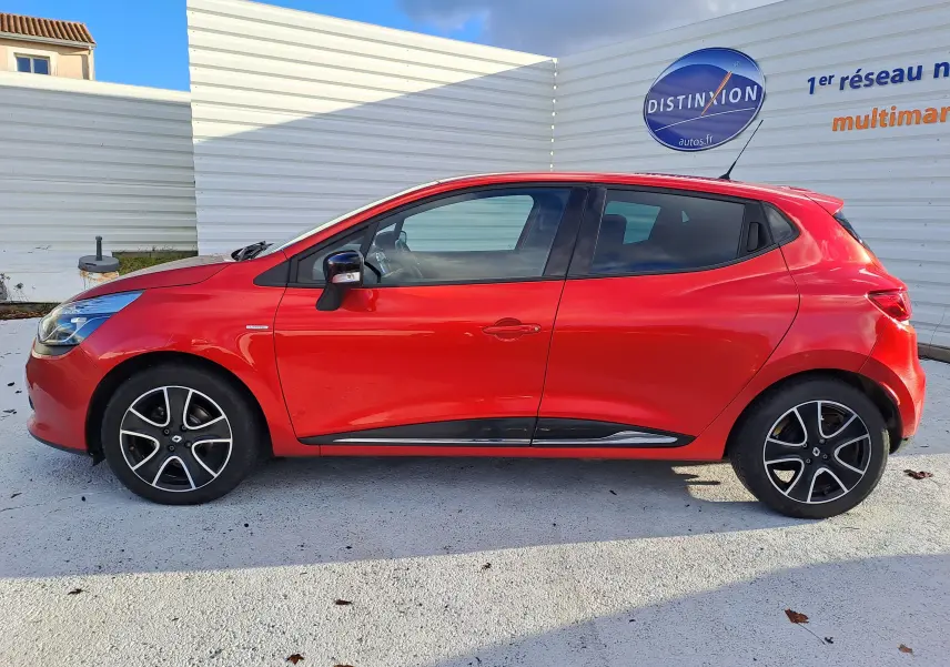Vue de profil côté gauche d'une Renault Clio IV rouge avec jantes alliage noires et détails chromés sur les portes.