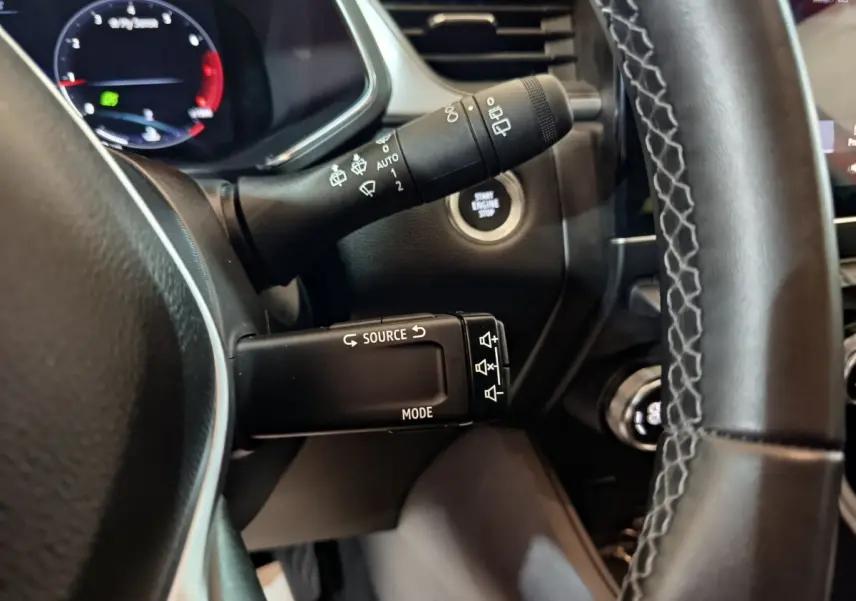 Gros plan sur la commande multifonctions et le bouton démarrage du tableau de bord du Renault Captur rouge 2024.