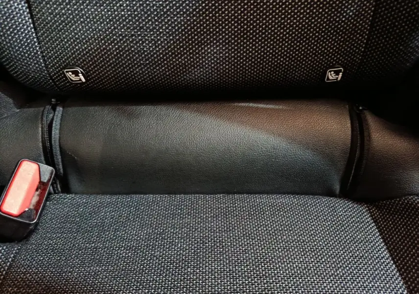Gros plan sur la banquette arrière noire du Renault Captur 2024, montrant les fixations Isofix et une boucle de ceinture rouge.