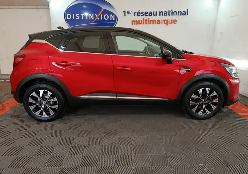 Profil latéral droit d'un Renault Captur rouge 2024 avec toit noir et jantes alliage bicolores.