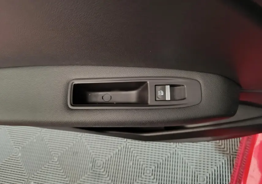 Gros plan sur la commande de lève-vitre côté conducteur d’une Renault Captur rouge, intérieur noir.