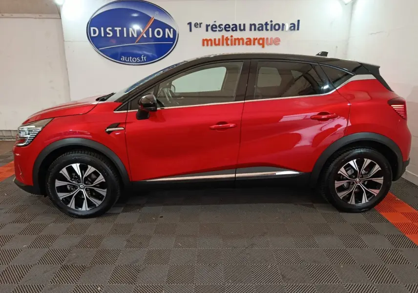 Profil droit d’un Renault Captur Techno TCe 90 rouge 2024 avec toit noir et jantes alliage bicolores.