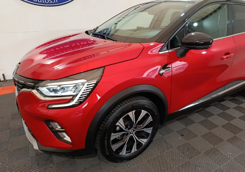 Vue 3/4 avant droit du Renault Captur Techno TCe 90 rouge avec toit noir et jantes alliage distinctives.