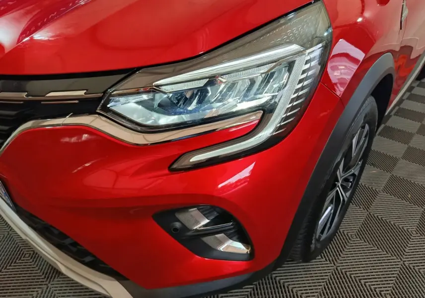 Gros plan sur l'avant droit rouge vif du Renault Captur 2024 avec phares LED et jante alliage visible.