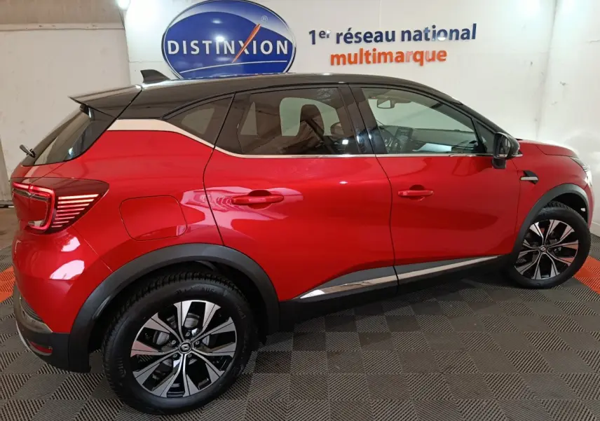 Vue latérale droite d’un Renault Captur Techno TCe 90 rouge 2024 avec toit noir et jantes alliage bicolores.