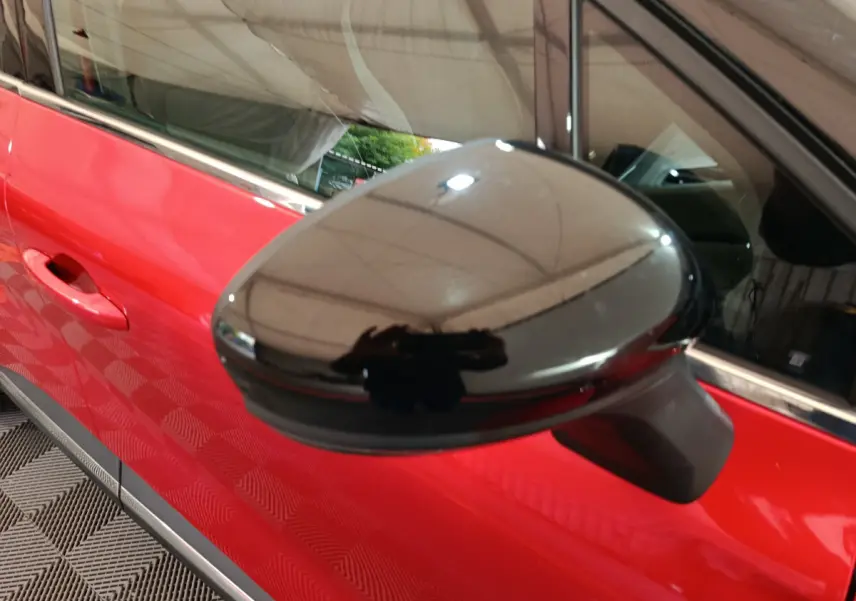Rétroviseur extérieur noir en gros plan sur le côté gauche d’un Renault Captur rouge 2024, vue rapprochée.