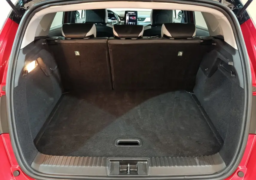 Coffre ouvert d’un Renault Captur rouge 2024, vue arrière montrant l’espace de chargement et les sièges arrière rabattables.