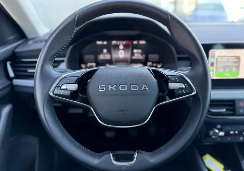 Vue rapprochée du volant en cuir noir de la Skoda Scala 2025 avec logo central et commandes intégrées.