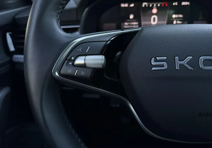 Gros plan sur le volant cuir noir de la Skoda Scala TSI 116, avec commandes multifonctions et tableau de bord digital flou.