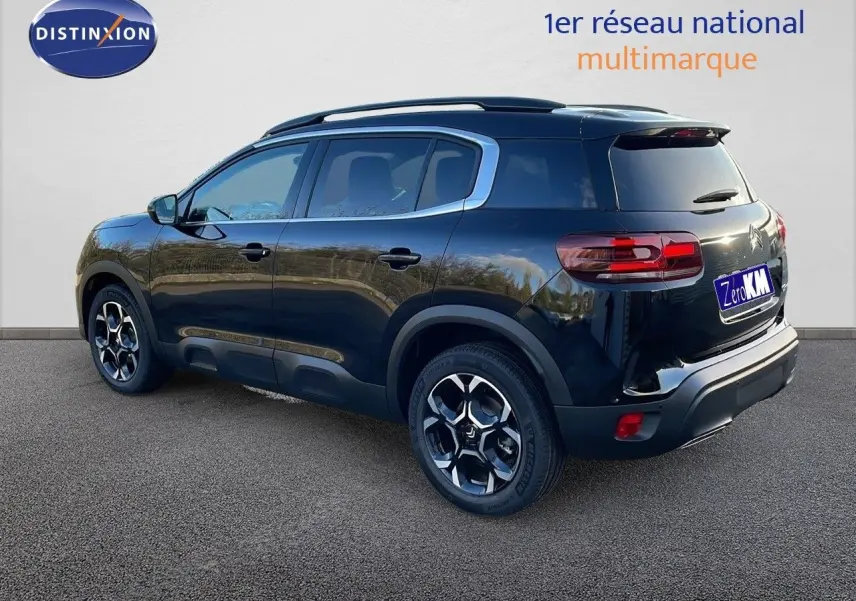 Vue 3/4 arrière droite d’un Citroën C5 Aircross noir perla metal avec jantes bi-ton et barres de toit visibles.