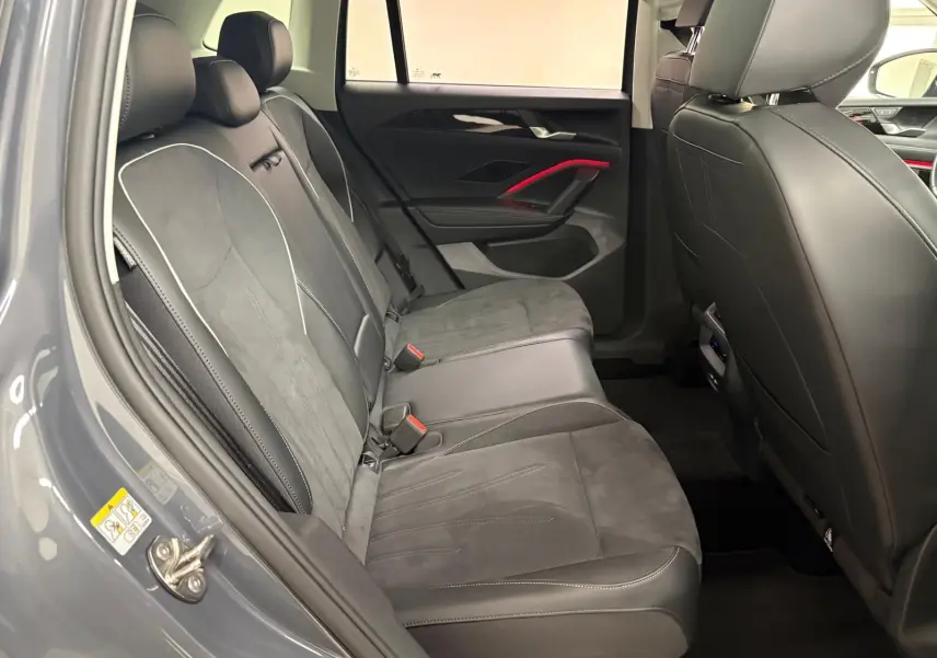 Vue intérieure côté arrière gauche du Volkswagen Tiguan 2025 gris Dauphin, montrant les sièges en cuir et alcantara avec surpiqûres contrastantes.