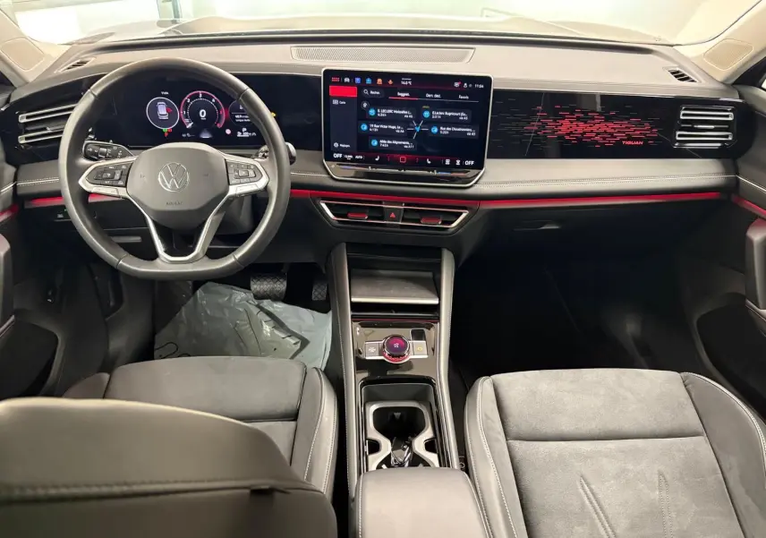 Vue intérieure frontale du Volkswagen Tiguan 2025 avec tableau de bord numérique, écran central tactile et sellerie grise.