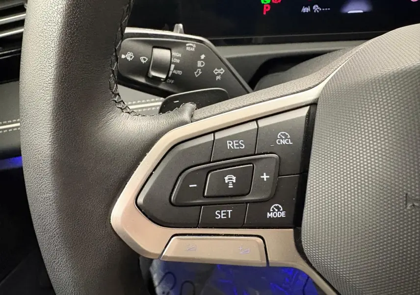 Gros plan sur les commandes au volant du Volkswagen Tiguan 2025, avec boutons de régulateur de vitesse et finition noire.