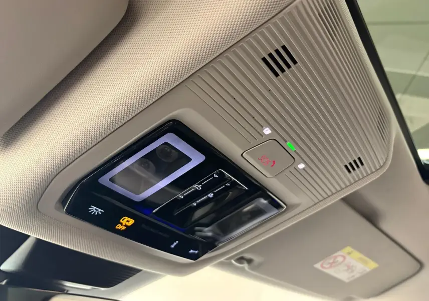Vue en gros plan du plafonnier intérieur beige avec commandes d’éclairage et bouton SOS du Volkswagen Tiguan 2025.