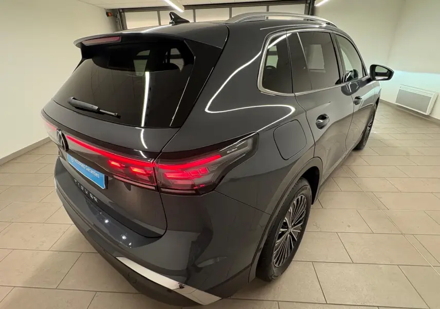 Vue 3/4 arrière droit du Volkswagen Tiguan 2.0 TDI 150 DSG7 Elegance gris dauphin métallisé avec feux arrière allumés.