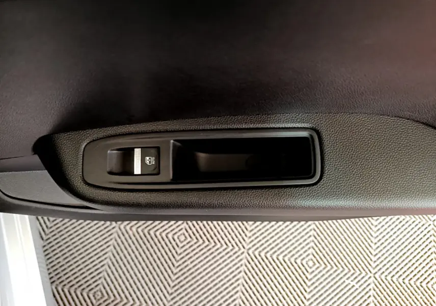 Détail de la commande de lève-vitre électrique sur la porte intérieure d’une Renault Clio Business gris clair.