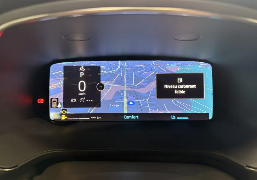 Tableau de bord numérique du Renault Captur E-Tech affichant une carte GPS et un message de niveau carburant faible.