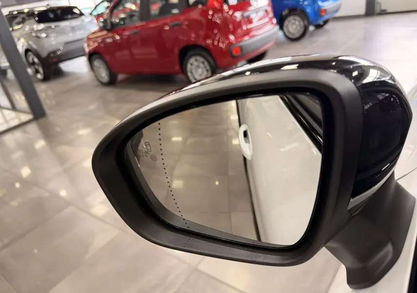 Rétroviseur côté droit noir brillant d’un Renault Captur blanc nacré avec toit noir, vue rapprochée en intérieur showroom.