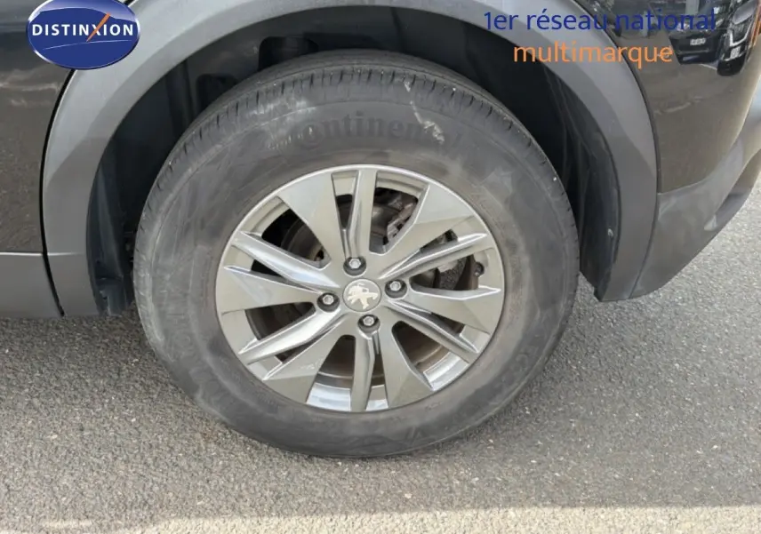 Gros plan sur la roue avant gauche du Peugeot 2008 noir perle métal avec jante alliage 16 pouces.
