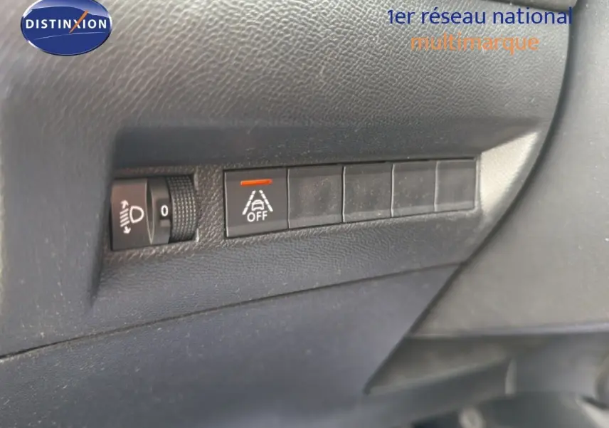 Gros plan sur les commandes de réglage des phares et désactivation de l'alerte de franchissement de ligne dans un Peugeot 2008 noir perle métal.