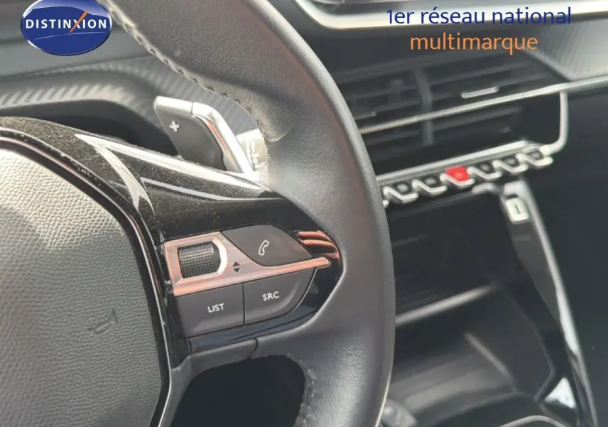 Gros plan sur le volant côté gauche du Peugeot 2008 noir perle métal, avec commandes intégrées et tableau de bord en arrière-plan.