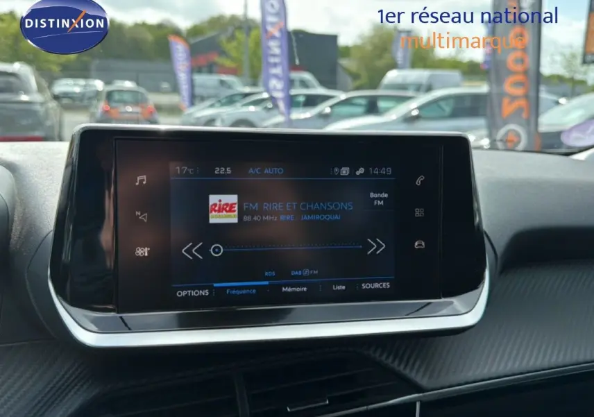 Vue rapprochée de l'écran tactile central du tableau de bord d'une Peugeot 2008 noir perle métal, affichant une radio FM.