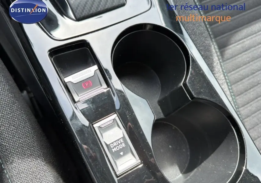 Gros plan sur la console centrale noire perle métal du Peugeot 2008, avec boutons frein à main électronique et mode de conduite.
