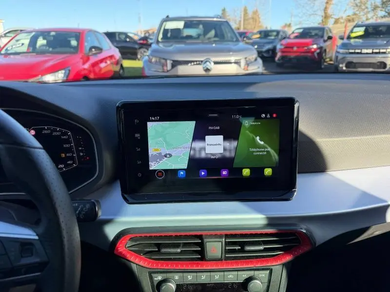 Vue intérieure du tableau de bord de la SEAT IBIZA 2025, écran tactile central avec cadre noir et contour d'aération rouge.