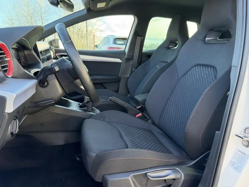 Vue intérieure côté conducteur de la SEAT IBIZA 2025 blanche, mettant en valeur les sièges sport et la console centrale.