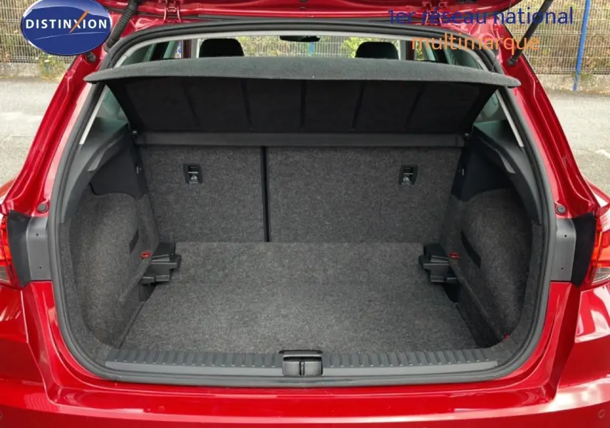 Coffre ouvert vu de l'arrière d'un SEAT Arona rouge désir métal avec toit noir, montrant l'espace de chargement vide.