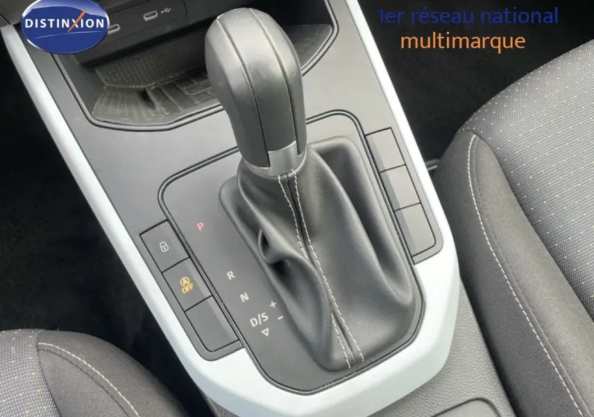 Gros plan sur le levier de vitesses automatique noir et la console centrale grise du SEAT Arona 2025, intérieur tissu gris.