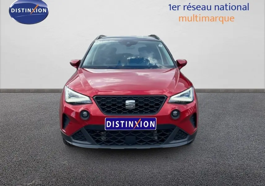 Vue frontale d'un SEAT Arona rouge désir métal avec toit noir, mettant en valeur ses phares LED et sa calandre noire.