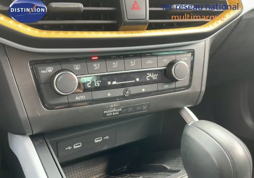Gros plan sur la console centrale de la SEAT Arona rouge désir métal, montrant la climatisation automatique et le levier de boîte auto.