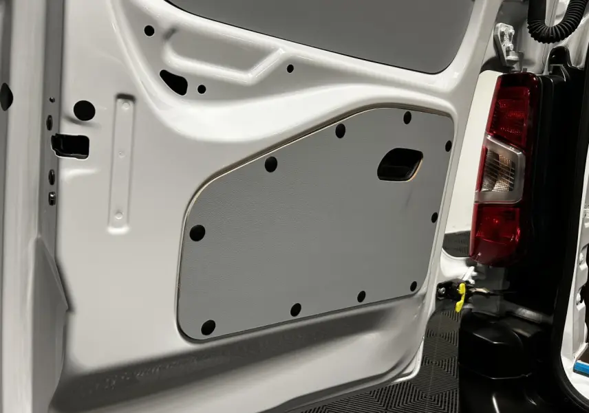 Gros plan sur la porte arrière droite blanche banquise du Peugeot Partner 2025, montrant le panneau intérieur gris et le feu arrière.
