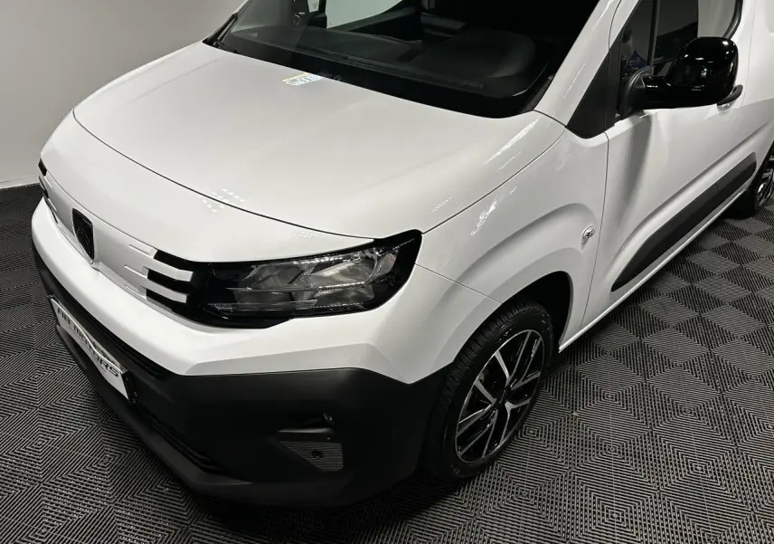 Vue 3/4 avant droit du Peugeot Partner blanc Banquise avec jantes alliage 17 pouces et rétroviseur noir brillant.