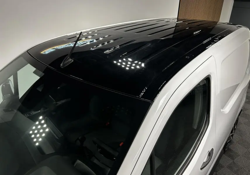 Vue plongeante 3/4 avant droit du Peugeot Partner blanc Banquise avec toit noir brillant et antenne sur le toit.
