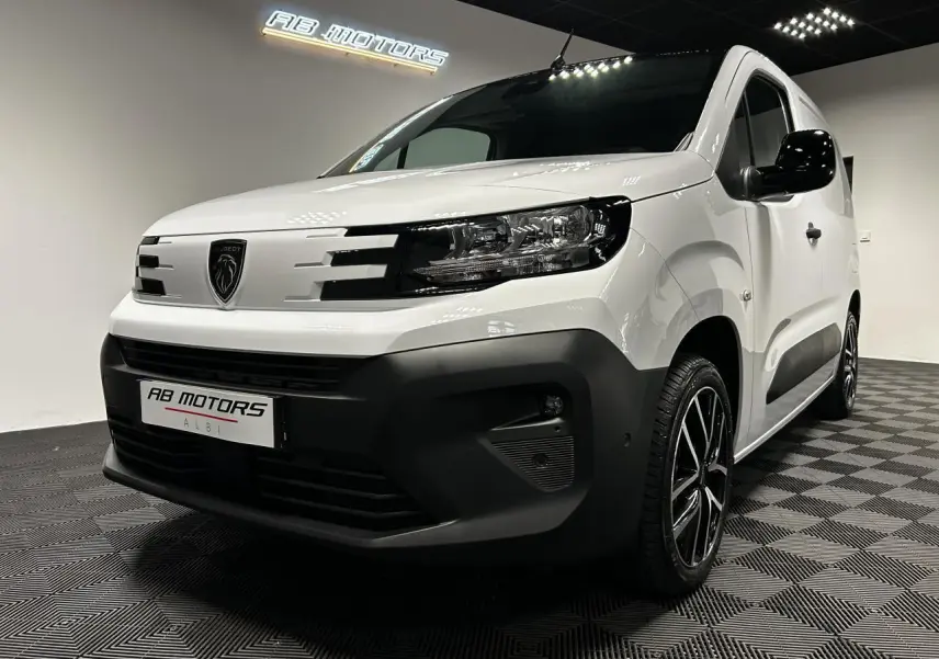 Vue 3/4 avant droit du Peugeot Partner blanc Banquise avec jantes alu 17 pouces et bouclier noir contrasté.