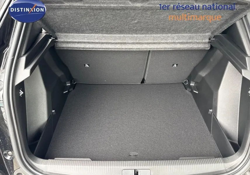 Coffre ouvert vu de l'arrière d'un Peugeot 2008 noir métal hybride 2025, espace de chargement vide et propre.