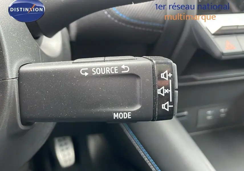 Gros plan sur la commande audio au volant du Renault Symbioz gris Rafale Métal, intérieur moderne avec surpiqûres bleues.