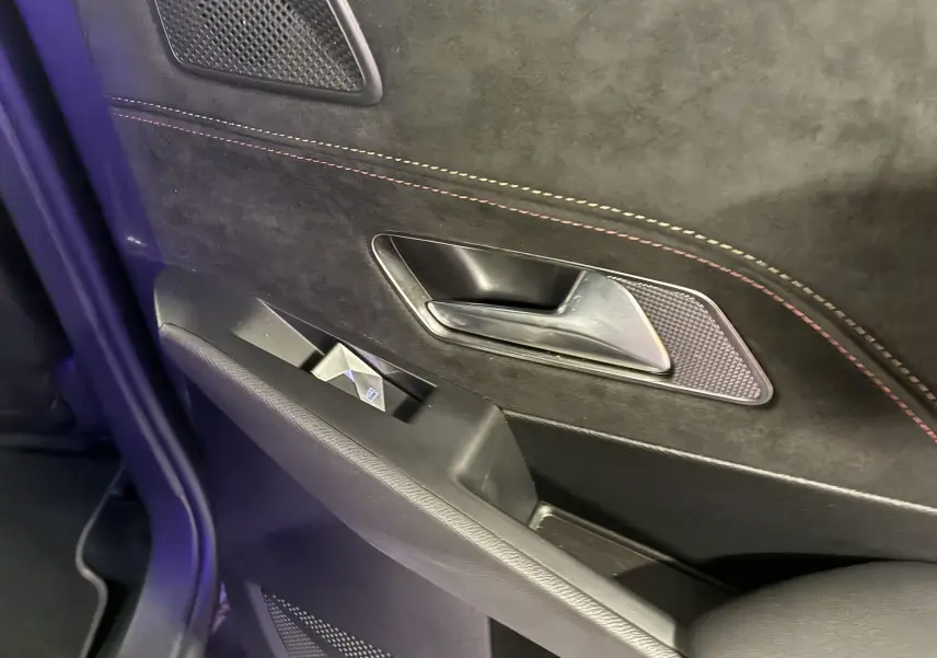 Gros plan sur la poignée intérieure et la commande de vitre de la porte côté gauche du DS7 E-TENSE gris, finition Performance Line.