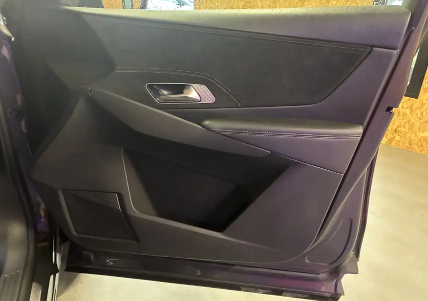 Vue intérieure de la porte côté gauche du DS7 E-TENSE 2024, finition noire avec surpiqûres apparentes et poignée métal.