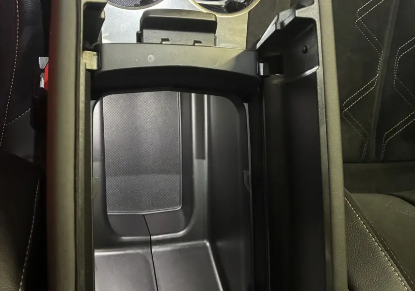 Vue plongeante sur la console centrale noire ouverte du DS7 E-TENSE 2024 avec porte-gobelets et clé posée.