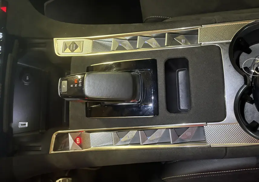 Vue rapprochée de la console centrale noire du DS7 E-TENSE 2024 avec levier de vitesse automatique et boutons argentés.