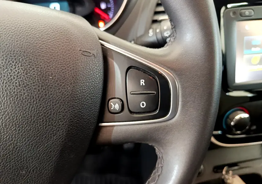 Gros plan sur le volant cuir multifonctions du Renault Captur gris foncé, avec commandes vocales et écran tactile visible.