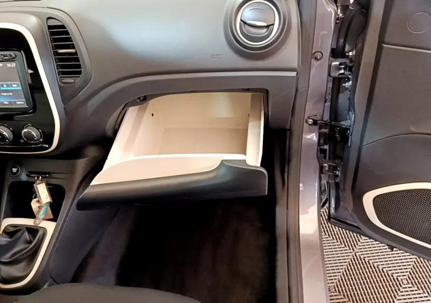 Intérieur Renault Captur Business gris foncé, vue côté passager sur boîte à gants ouverte et console centrale avec levier de vitesses manuel.