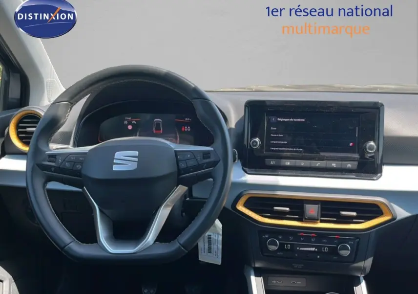 Vue intérieure centrée sur le volant et le tableau de bord du SEAT Arona gris avec détails dorés autour des aérateurs.