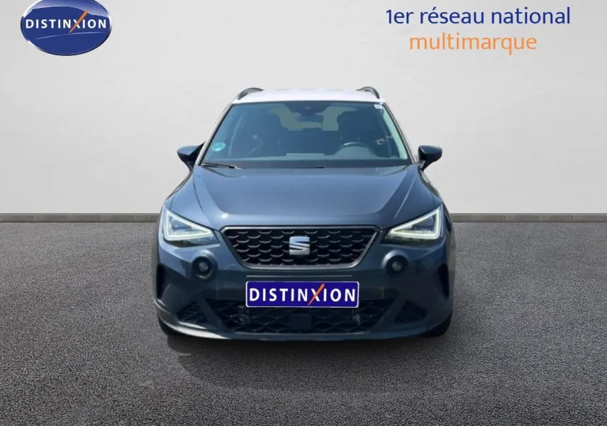Vue avant d'un SEAT Arona gris Magnetic Metal avec toit blanc, mettant en valeur ses phares LED et sa calandre distinctive.